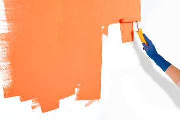 Worker painting white wall orange with paint roller