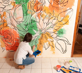 Female painter creating unusual design on wall in her apartment