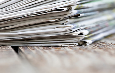 Morning news concept - newspapers stack close-up with copy space on wooden background
