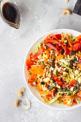 Asian coleslaw salad with white cabbage, carrot, pepper, sesame and cashew nuts. Healthy food concept. Light concrete background. Copy space.