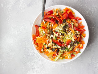 Asian coleslaw salad with white cabbage, carrot, pepper, sesame and cashew nuts. Healthy food concept. Light concrete background. Copy space.