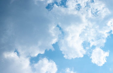 Blue sky and white clouds blue sky on a bright day with white clouds coming in floating come to cover sun causes a white beam causing beauty in the sky.