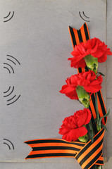 May 9 Victory day card. Red carnations and St. George ribbon on the background of an old photo album. Day of memory and military glory.