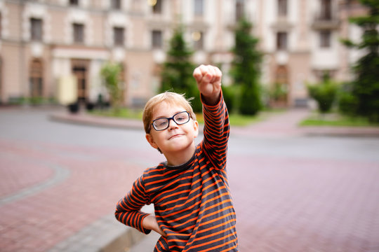 Funny smiling superhero boy pointing at camera, he is wearing a Union Jack flag as a cape - Powered by Adobe