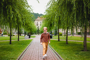 Fototapeta na wymiar Young happy boy running in the grass at the park on a summer day