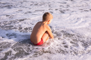 Fototapeta premium Boy jumping in sea waves. Jump accompanied by water splashes. Summer sunny day, ocean coast