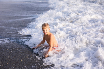 Fototapeta premium Boy jumping in sea waves. Jump accompanied by water splashes. Summer sunny day, ocean coast