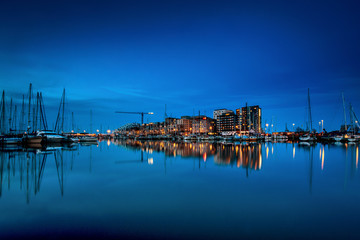 Fototapeta na wymiar Aarhus Ø seen at night time with water reflections and Aarhus Marina in the foreground