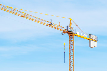 Tower crane with slings against blue sky