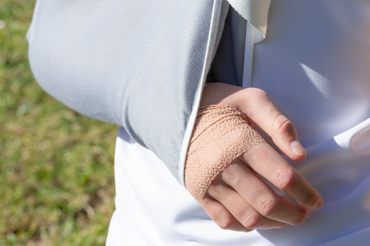 A boy with an injured hand in a fixing bandage on the background of a football field,