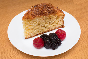 a piece of homemade coconut cake with berries strawberry and blackberry