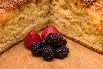 a piece of homemade coconut cake with berries strawberry and blackberry