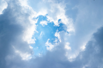 Blue sky and white clouds blue sky on a bright day with white clouds coming in floating come to cover sun causes a white beam causing beauty in the sky.