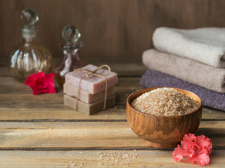 Sea salt, natural handmade soap, natural cosmetic oil and colorful towels with azalea flowers on rustic wooden background