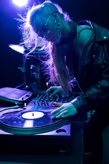 beautiful blonde dj girl touching vinyl record in nightclub
