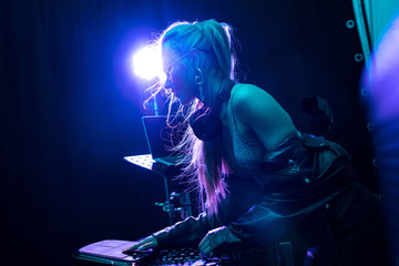 blonde stylish dj girl touching dj equipment in nightclub