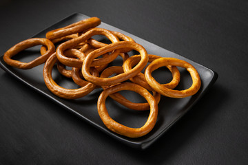 Dry bread rings, crackers stacked in a black plate on a black background.