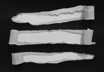 Piece of torn paper on black. Copy space