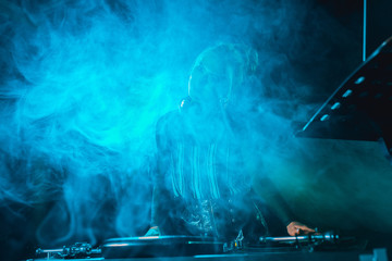 dj girl using dj equipment in nightclub with smoke