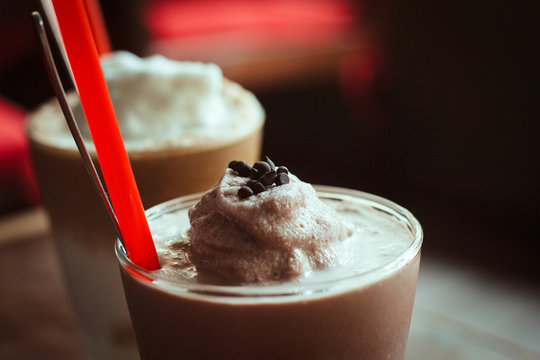 Closeup Photo Of Delicious Ice Blended Cocoa With Coconut Milk And Small Pieces Of Chocolate And Ice Blended Coconut Coffee In The Cafe In Background