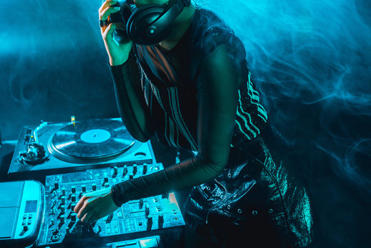 cropped view of dj woman using dj mixer in nightclub with smoke