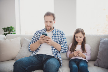 Portrait of his he her she nice-looking cute attractive pre-teen candid girl trendy handsome bearded dad sitting on divan using cell in light white interior room indoors