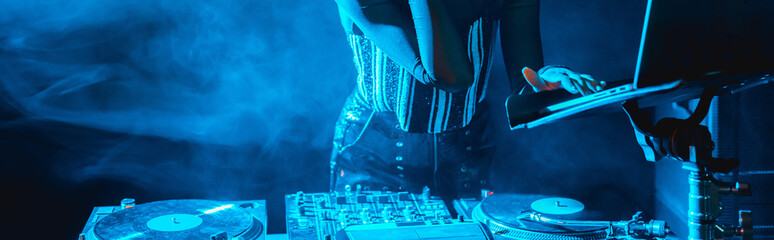 panoramic shot of dj woman using laptop in nightclub with smoke - obrazy, fototapety, plakaty