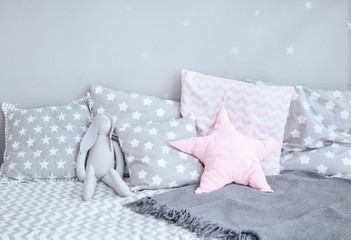 Modern baby bed with gray pillows. Close-up
