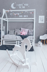 White wooden rocking horse in stylish wooden children room