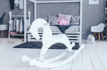 White wooden rocking horse in stylish wooden children room