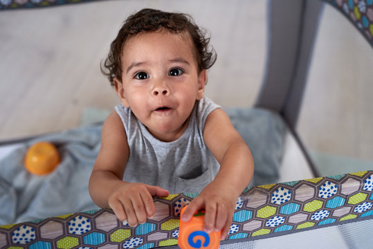 Portrait of cute hispanic baby standing in cot