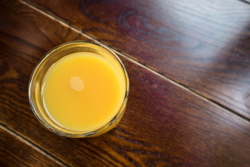 Large glass of Orange Juice fruit cold drink on a dark wood table.  Top down overhead view