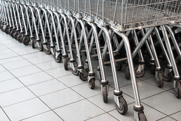 Rows of Metal Shopping Trollies outside shop ready for shoppers to use.