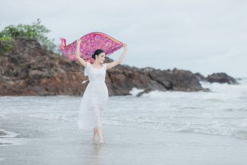 young girl in a beautiful white dress walking on the beach evening time on weekend summer holiday...