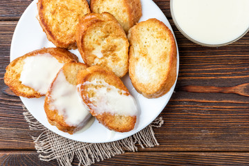 French toasts with condensed milk on dark wooden background.