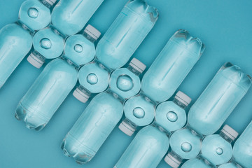 top view of plastic water bottles arranged in rows isolated on turquoise