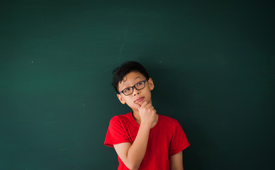 Asian boy with book on blackboard background education school classroom concept