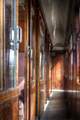 Interior shot of vintage railway carriage corridor showing wooden fittings, windows to one side and compartments to the other.