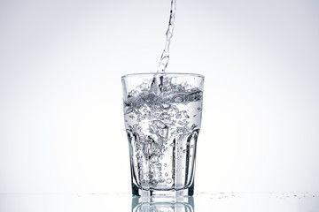 water pouring in drinking glass on white background with backlit and copy space