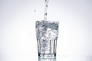 water pouring in drinking glass on white background with backlit and copy space