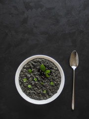 Soup puree of black beans on black background. 
