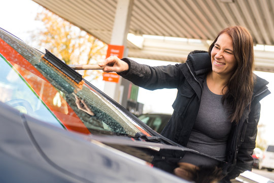 Junge Frau reinigt die Frontscheibe ihres Autos