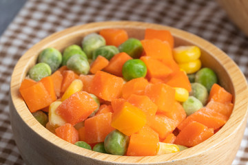 carrots corns and peas on wooden bowl