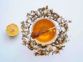 Obraz na płótnie Canvas Teezeit, Eine Tasse Tee und loser Kräutertee, Zitrone und Kandiszucker auf einem weißen Hintergrund
