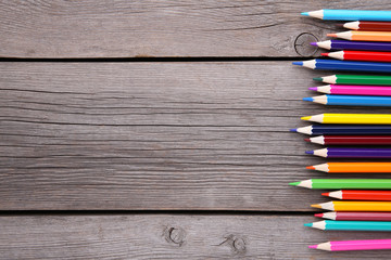 Many different colored pencils on a grey wooden background