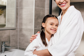 daughter and mother hugging and smiling in bathroom