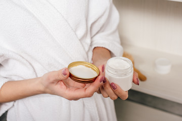 cropped view of woman holding container with cosmetic cream in bathroom