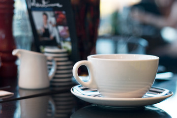 Steaming hot drink in a white cup on a cafe table.  Lunching, meeting friend for a chat, take a break, hot drink concept.