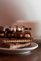 Chocolate biscuit snapper in half on a saucer in front of a white tea cup or coffee cup.  Coffee shop, tea shop, cuppa with friends, relaxing, take a break concepts.