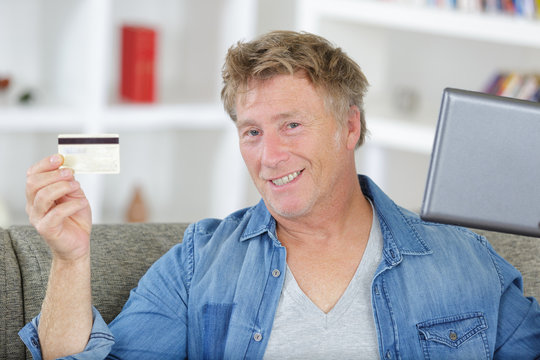 Mature Man Using His Laptop And Holding His Credit Card